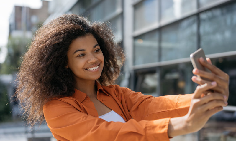 A young black woman taking a selfie on her smart phone.