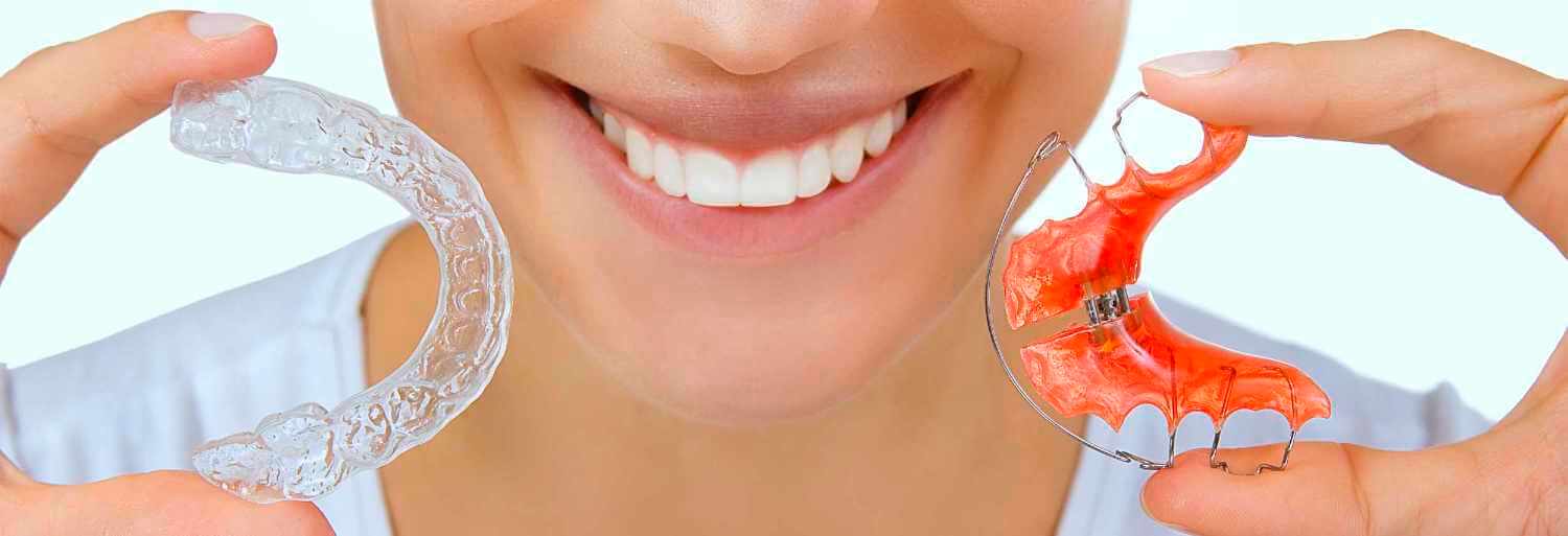 Woman holding clear and traditional braces.