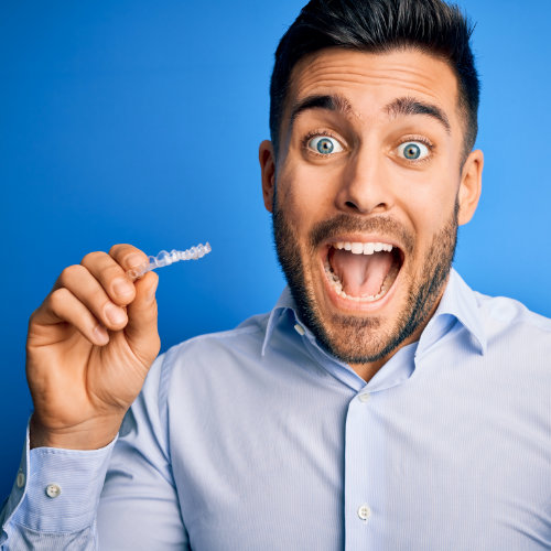 Smiling man holding Smiles Club Clear Aligners and showing great teeth.